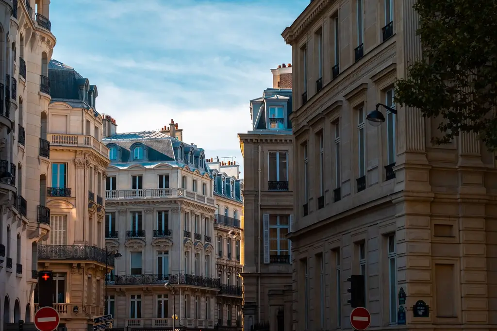 Rue bordée d’immeubles haussmanniens sous un ciel bleu